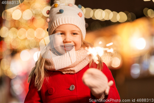 Image of happy girl with sparkler at christmas market