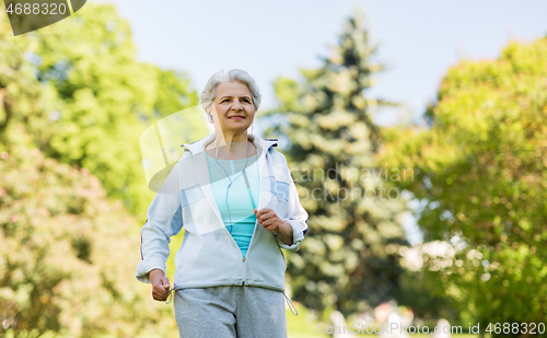 Image of senior woman with earphones running in summer park