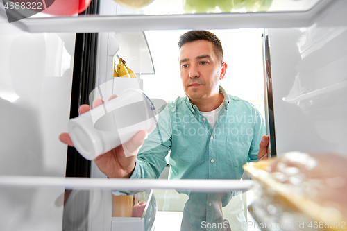 Image of man taking food from fridge at kitchen