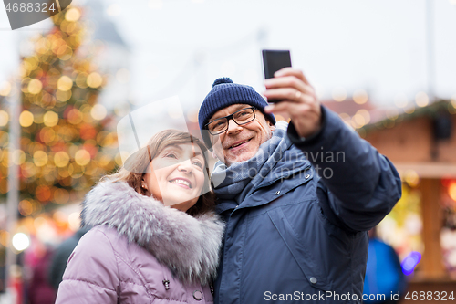 Image of senior couple taking selfie at christmas market