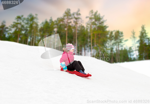 Image of happy little girl sliding down on sled in winter