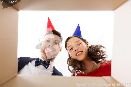 Image of couple in party hats opening birthday gift box