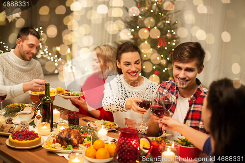 Image of happy friends drinking red wine at christmas party