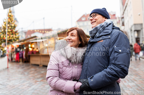 Image of happy senior couple hugging at christmas market