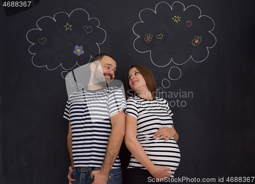 Image of pregnant couple posing against black chalk drawing board