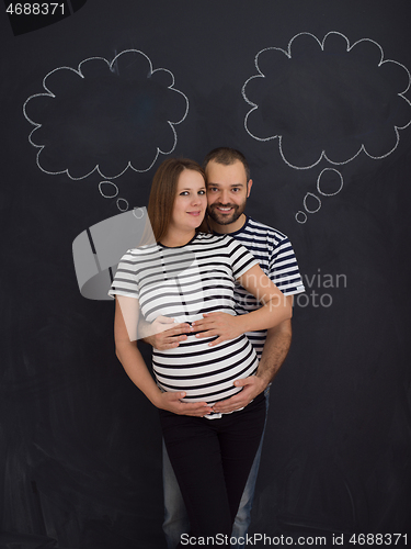 Image of pregnant couple posing against black chalk drawing board