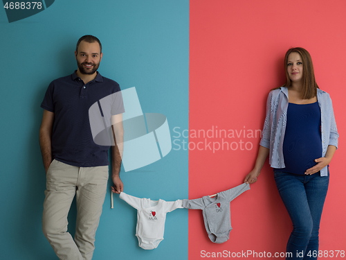 Image of young couple holding baby bodysuits