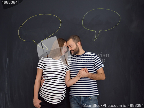 Image of pregnant couple posing against black chalk drawing board