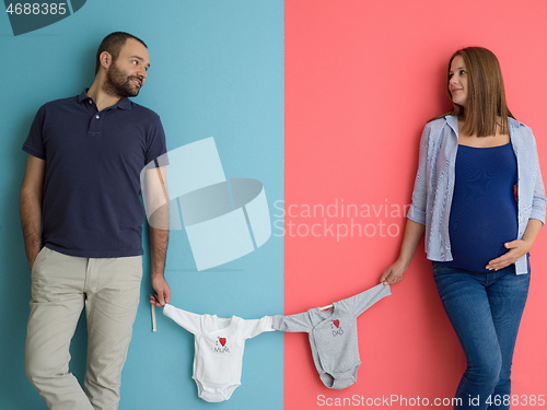 Image of young couple holding baby bodysuits