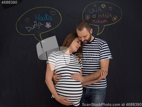 Image of pregnant couple posing against black chalk drawing board