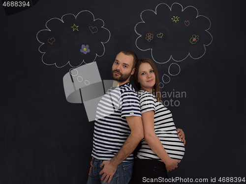 Image of pregnant couple posing against black chalk drawing board