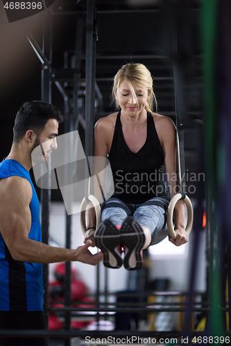 Image of woman working out with personal trainer on gymnastic rings