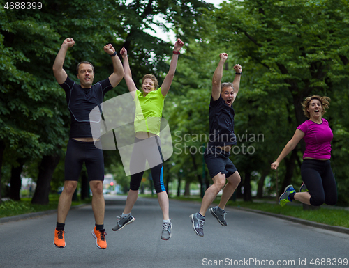 Image of runners team jumping in the air during  morning training