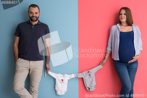 Image of young couple holding baby bodysuits