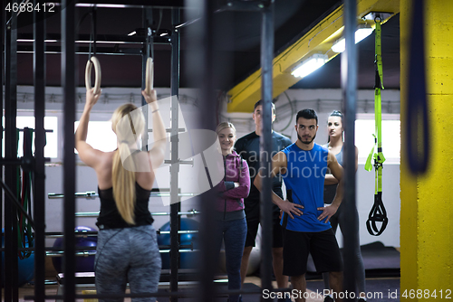 Image of woman working out with personal trainer on gymnastic rings
