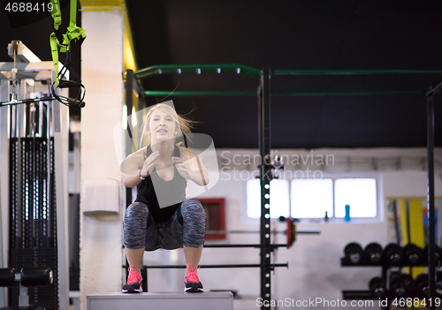 Image of woman working out  jumping on fit box