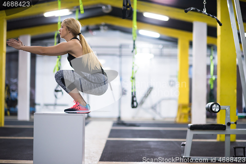 Image of woman working out  jumping on fit box