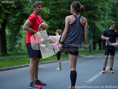 Image of runners team warming up and stretching before morning training