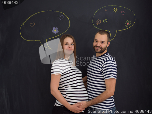 Image of pregnant couple posing against black chalk drawing board