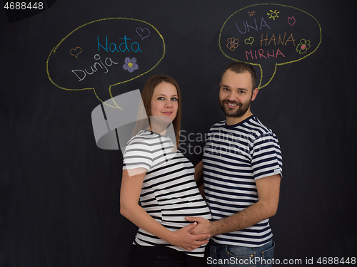 Image of pregnant couple posing against black chalk drawing board
