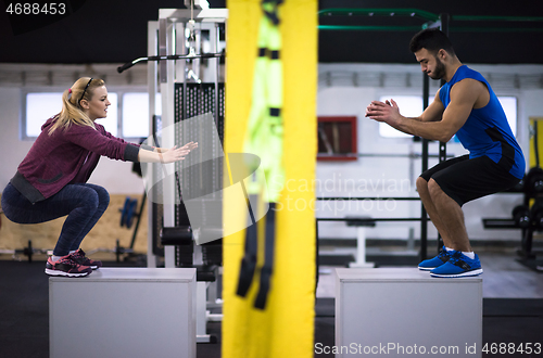 Image of athletes working out  jumping on fit box