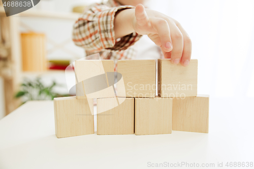 Image of Little child sitting on the floor. Pretty boy palying with wooden cubes at home