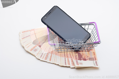 Image of Against the background of five thousandth bills, there is a grocery basket in which the phone lies