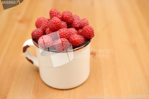 Image of large ripe raspberries in a mug 
