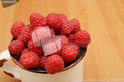 Image of large ripe raspberries in a mug 