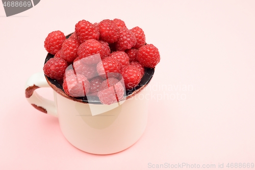 Image of large ripe raspberries in a mug 