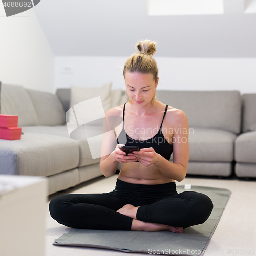 Image of Beautiful blonde woman doing home workout indoors. Woman practice yoga at home. Fit girl using workout tutorials for healthy active lifestyle. Woman using quarantine for home workouts.