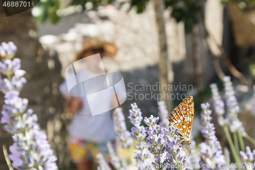 Image of Out of focused image of young female traveler wearing straw sun hat enjoying summer on Mediterranean cost strolling among lavander flowers on traditional costal village garden.