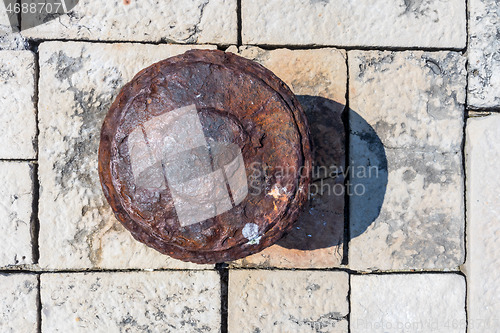 Image of Old rusted mooring bollard on old stone pier background