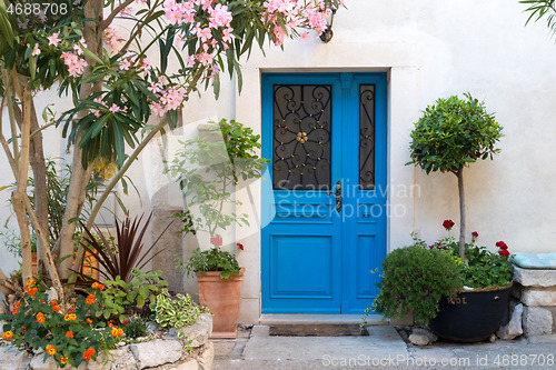 Image of Beutiful vintage courtyard with lush greenery and marine blue wooden door in old Mediterranean costal town, Croatia