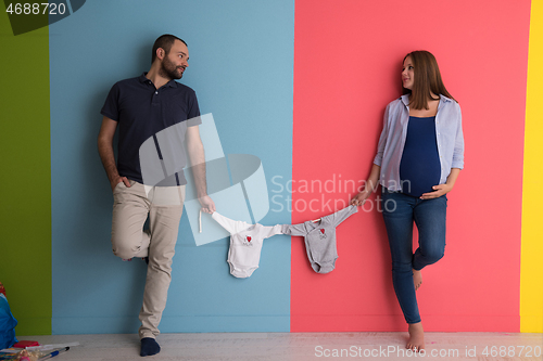 Image of young couple holding baby bodysuits