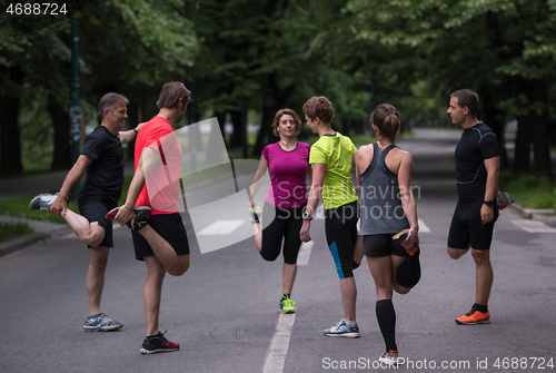 Image of runners team warming up and stretching before morning training