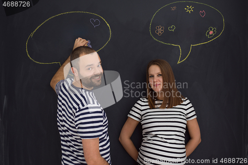 Image of pregnant couple writing on a black chalkboard