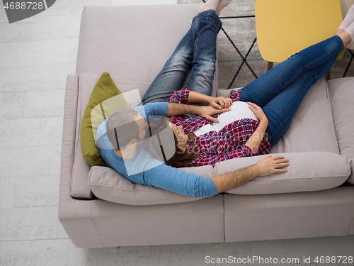 Image of pregnant couple relaxing on sofa