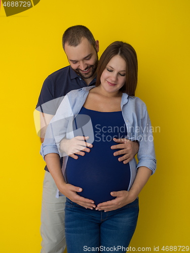 Image of pregnant couple  isolated over yellow background