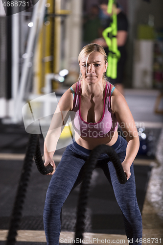 Image of athlete woman doing battle ropes cross fitness exercise