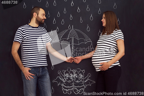 Image of pregnant couple drawing their imaginations on chalk board