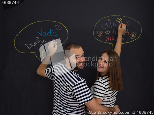 Image of pregnant couple writing on a black chalkboard