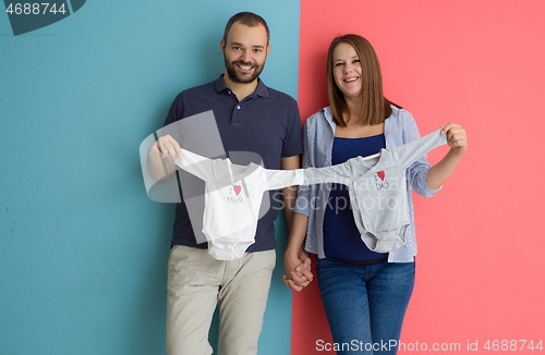 Image of young couple holding baby bodysuits