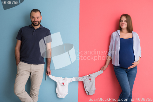 Image of young couple holding baby bodysuits