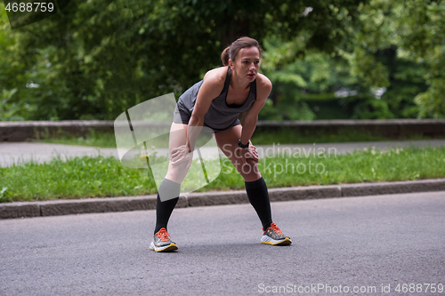 Image of female runner warming up and stretching before morning training