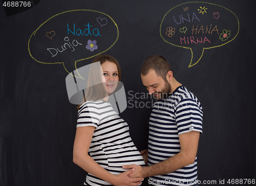 Image of pregnant couple posing against black chalk drawing board