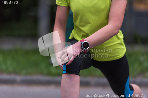 Image of female runner warming up and stretching before morning training