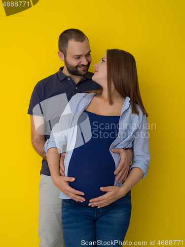 Image of pregnant couple  isolated over yellow background