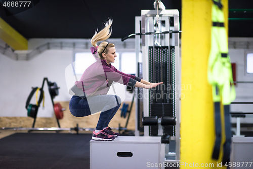 Image of woman working out  jumping on fit box