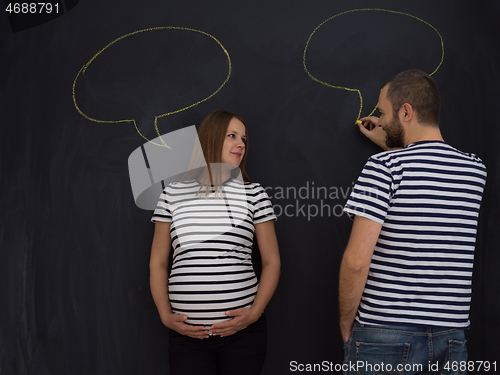 Image of pregnant couple writing on a black chalkboard